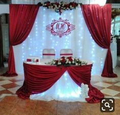 a red and white wedding reception setup with draping, flowers, and lights