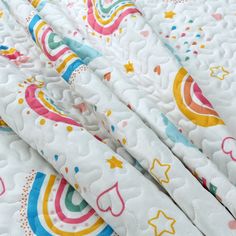 a close up view of a white quilt with rainbows and stars on it