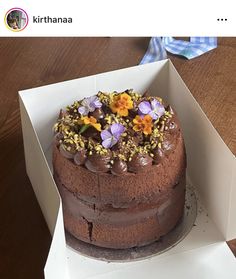 a chocolate cake in a box with flowers on top