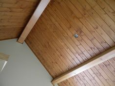 a bedroom with wood paneling on the ceiling and bed in the corner next to it