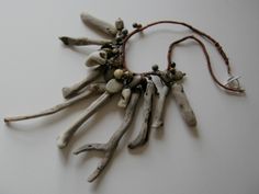 a necklace made out of driftwood and beads on a white surface with a brown cord