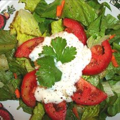 a salad with tomatoes, lettuce and ranch dressing