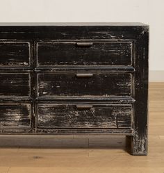 an old black dresser with drawers on the bottom and one drawer open, sitting on a wooden floor