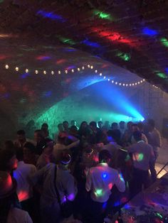 a group of people standing around in a room with colored lights on the walls and ceiling