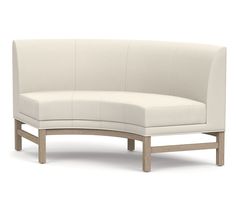 a white curved couch sitting on top of a wooden frame