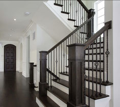 an elegant staircase with black railing and wood handrails in a white home setting