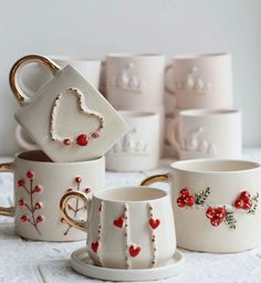 several cups and saucers with hearts painted on them are sitting next to each other