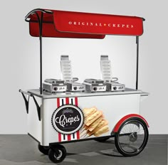 an old fashioned ice cream cart with food on the top and wheels, in front of a gray background