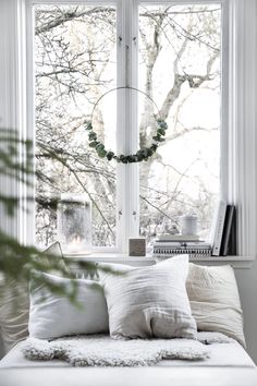 a white couch sitting under a window in front of a wreath on top of a window sill