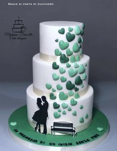 a white and green wedding cake with hearts on it