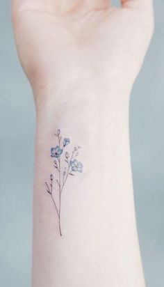 a small blue flower tattoo on the wrist