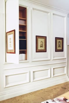 an empty room with white walls and framed pictures on the wall, along with bookshelves