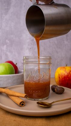 an apple cider being poured into a glass jar