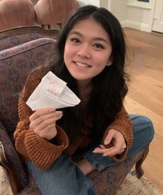 a woman sitting on a chair holding a piece of paper