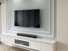 a flat screen tv mounted to the side of a white wall in a living room