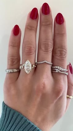 a woman's hand with three different rings on her fingers and one ring in the middle