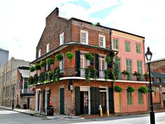 an old brick building with green plants on the windows and balconies above it