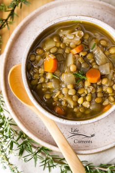 a white bowl filled with soup on top of a wooden table next to a spoon