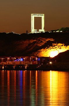 the lights are on and reflecting in the water at night, with an arch shaped like a door