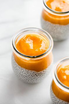 three jars filled with orange colored food on top of a white countertop next to each other