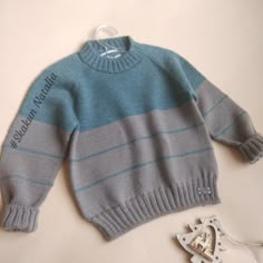 a blue and gray striped sweater next to a pair of scissors on a white surface