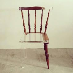 a wooden chair sitting on top of a cement floor next to a white wall,