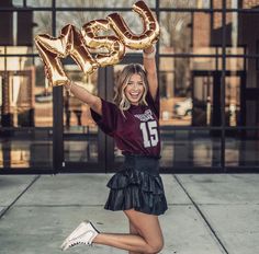 a woman holding up the letters that spell out her name in front of a building