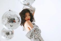 a woman is posing in front of disco balls