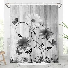 a shower curtain with white flowers and butterflies on it in front of a wooden wall