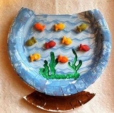 a paper plate shaped like a fish bowl with goldfish in the water on it