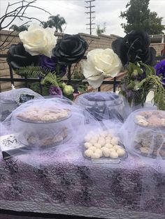 there are many desserts on the table with purple and white flowers in the background