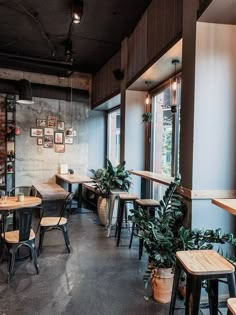 the interior of a restaurant with tables and chairs, potted plants on the wall