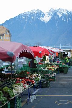 an outdoor farmers market with mountains in the background