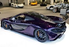 a purple sports car is on display in a showroom with other cars behind it