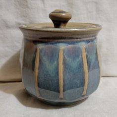 a blue and brown ceramic container with a wooden spoon in the top right hand corner