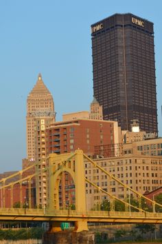 the bridge is going across the river with tall buildings in the background