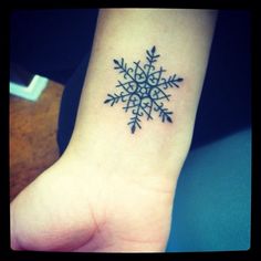 a small snowflake tattoo on the wrist