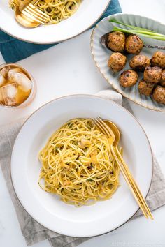 two plates of spaghetti and meatballs on a white table with chopsticks next to them