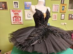 a dress made out of tulle and feathers on display in a room with green walls