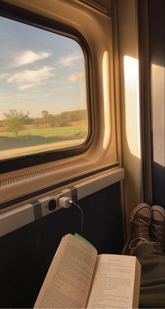 an open book sitting on top of a seat next to a window in a train