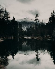 a lake surrounded by trees and mountains in the background