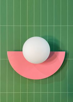 an egg sitting on top of a pink piece of paper next to a green tile wall