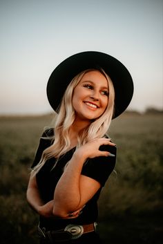 a woman wearing a black hat standing in a field