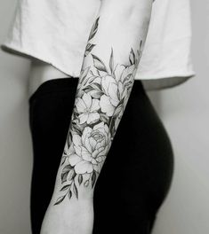 a woman's arm with flowers and leaves tattooed on her left arm, in black and white