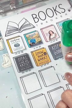 a hand holding a green marker next to a book with books on it and other items