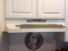 a kitchen with white cupboards and a metal plate on the counter top that has been stripped off