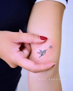 a woman's left hand with a small tattoo on her right arm, and a tiny humming