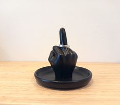 a black ring is placed on top of a black holder that holds a finger in the shape of a hand