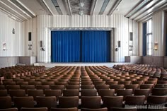 an empty auditorium with blue curtains and chairs