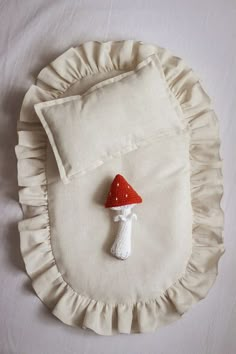 a white pillow with a red hat on it and a small stuffed mushroom attached to the pillow